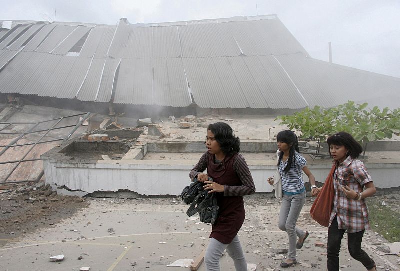 Students run near a collapsed university building after an earthquake hit Padang, on Indonesia's Sumatra island