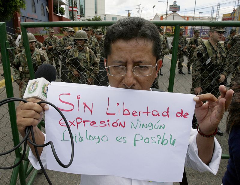 A Radio Globo journalist holds a placard during a protest in front of the Presidential House in Tegucigalpa