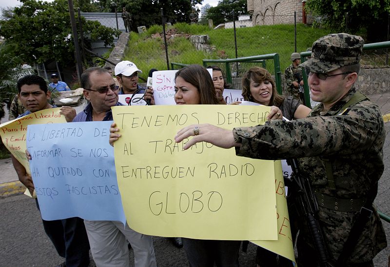 Radio Globo journalists hold placards demanding media freedom during a protest in front of the Presidential House in Tegucigalpa