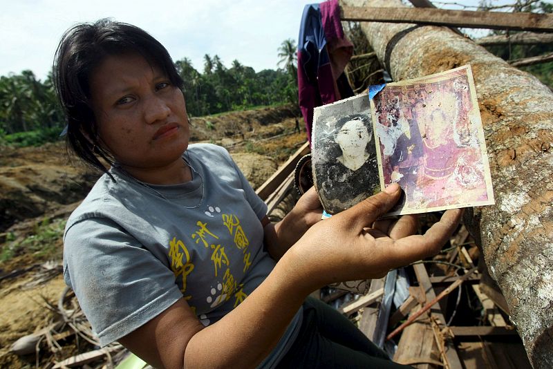 Una superviviente muestra las fotos de sus familiares muertos en un corrimiento de tierras provocado por el terremoto.