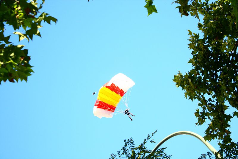 Tres paracaidistas han sido los encargados de bajar desde el cielo la bandera que ha presidido el desfile desde la plaza de Lima.