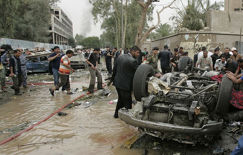 Security officials gather around an overturned car to rescue the victims after two car bombs targeting the Ministry of Justice and the Baghdad Provincial Council exploded in central Baghdad