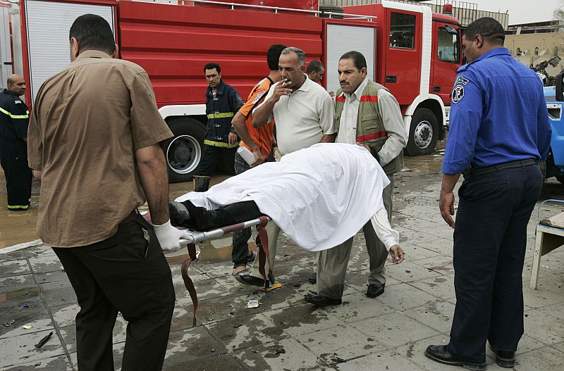 Security officials take a dead man to the morgue after two car bombs targeting the Ministry of Justice and the Baghdad Provincial Council exploded in central Baghdad