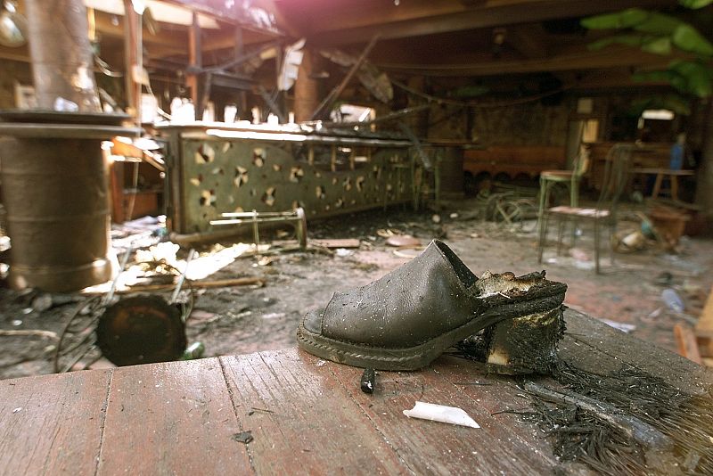 A SINGED SHOE ON TABLE IN DESTROYED BAR AFTER A BOMB BLAST IN KUTA, BALI.
