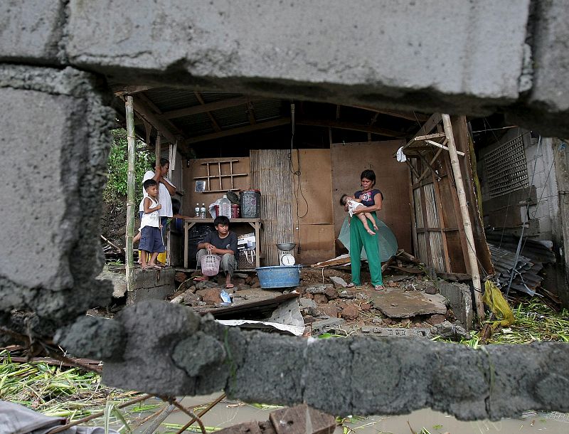 Una familia contempla desolada su casa destruida, en la población de Cardona, en la provincia de Rizal (Filipinas),