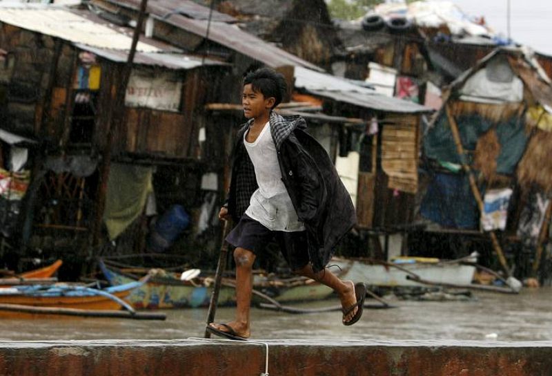 Un niño corre en medio fuertes vientos y calle inundadas en Bacoor, en la provincia de Cavite, Filipinas.