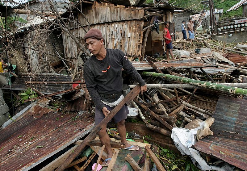 Un hombre rescata algunas pertenencias de lo que queda de su casa, tras el fuerte azote de las olas en la población de Cardona en Filipinas.