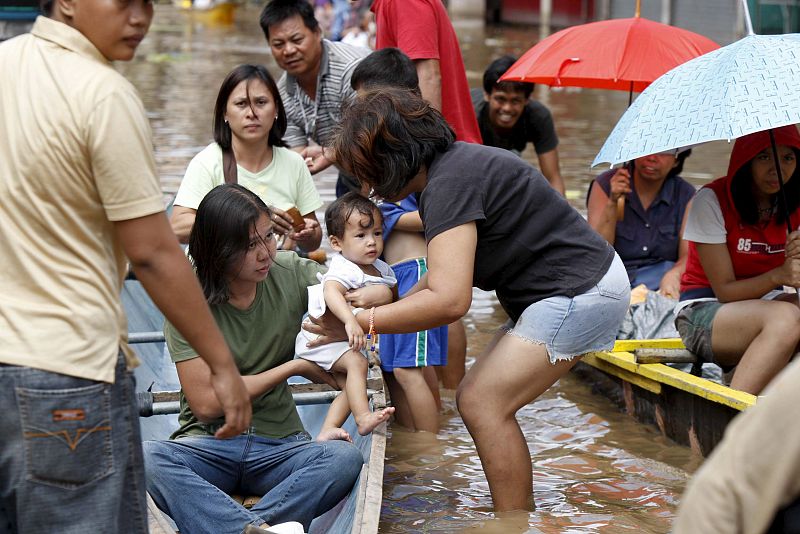 Los filipinos huyen de sus hogares, anegados de agua, mediante canoas en la población de Santa Cruz.