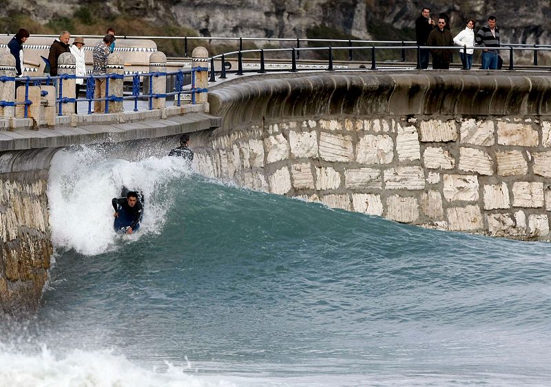 Un surfista aprovecha las grades olas formadas en el paseo del Sardinero como consecuencia del fuerte viento que se registra en Santander.