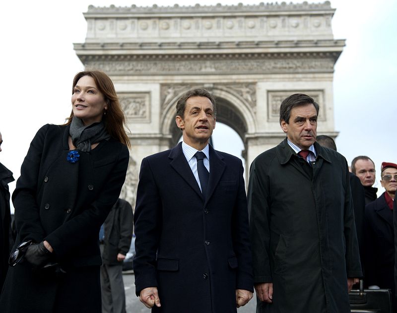 El presidente francés, Nicolas Sarkozy, acompañado de su esposa, Carla Bruni, y el primer ministro, Francois Fillon, abandonan el acto de conmemoración del armisticio que puso fin a la Primera Guerra Mundial.