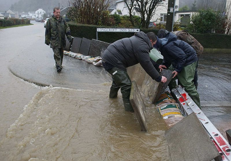 Residents construct a homemade barrier as they try to hold back rising flood water in the village of Braithwaite