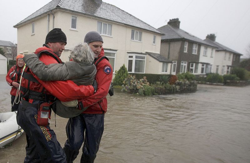 Rescue workers carry an elderly woman out of flood water in Keswick