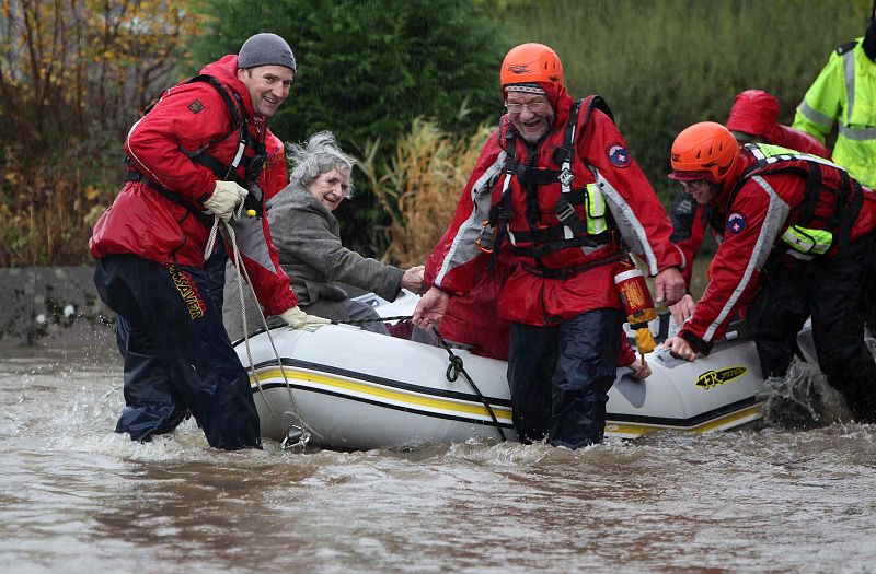 Rescue workers ferry an elderly woman out of flood water in Keswick