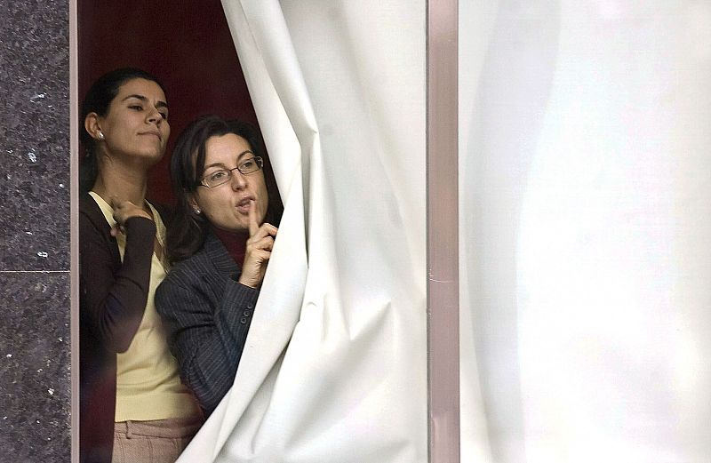 Unas empleadas de Cajacírculo hacen señas a través del cristal después de haber sido retenidas en el interior del establecimiento.