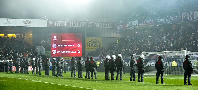 Oficiales de la policía antidisturbios tratan de evitar que aficionados radicales del Austria de Viena invadan el terreno de juego del estadio Franz Horr.