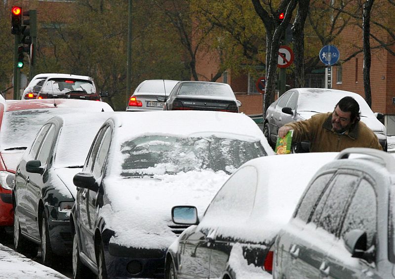 Nieve sobre los vehículos estacionados en una calle de Madrid.