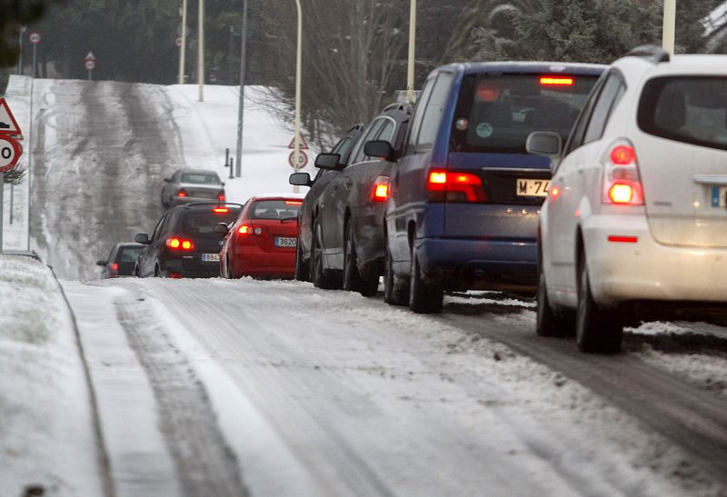 Varios vehículos tratan de avanzar hacia el centro de Madrid entre las placas de hielo en la carretera.