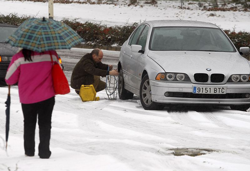 Un conductor coloca las cadenas a su vehículo para poder circular en el hielo.