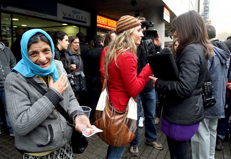 Una mujer pide limosna ante la Administración de la Lotería Valdés, que repartierón el tercer premio, número 10.104 y el cuarto premio, número 29.013