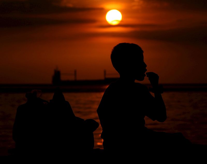 Un muchacho filipino oberva el atardecer en la bahía de Manila (Filipinas)