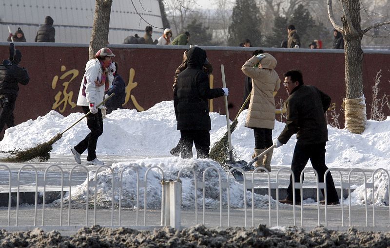 Members of the public shovel snow from footpaths near Beijing's Tiananmen Square