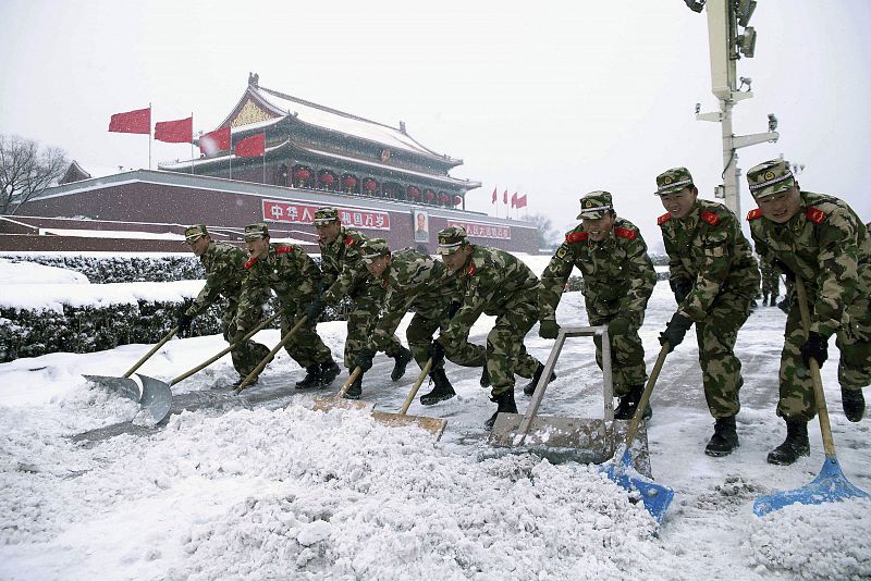 Paramilitary policemen shovel snow on Tiananmen Square in Beijing