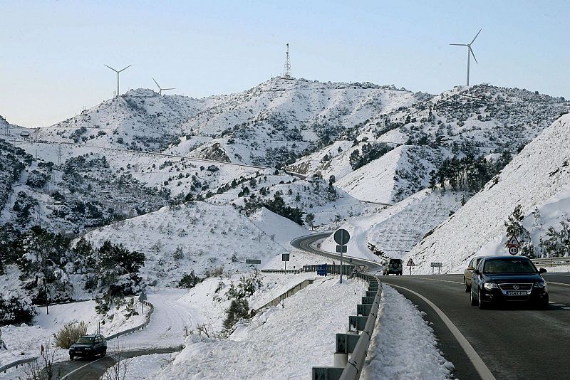 Varios vehículos circulan por la carretera N-420 a su paso por el Coll de la Teixeta, en Tarragona, que presenta este aspecto debido al temporal de nieve que afecta a la zona.