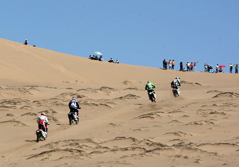 Un grupo de motoristas asciende una duna a la salida de la etapa en Copiapó.
