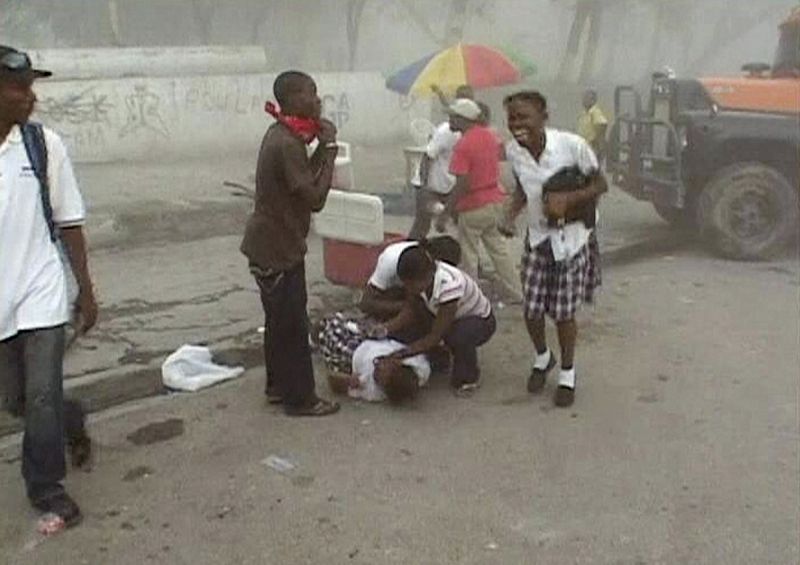 People react as a woman collapses on a street after a major earthquake struck, in Port-au-Prince
