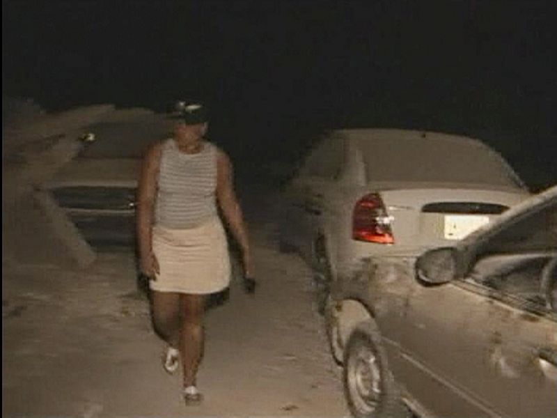 A woman walks past a car near to Port-au-Prince University after a major earthquake struck, in Port-au-Prince