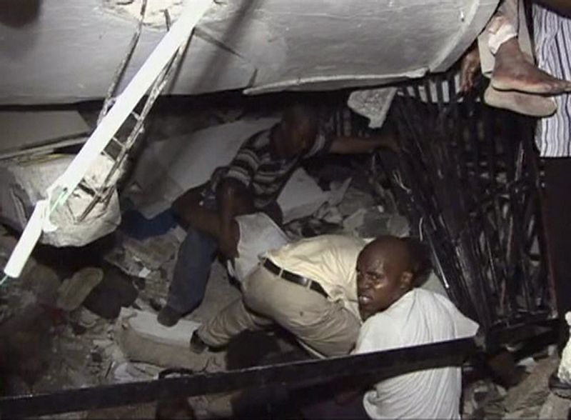 Men try to help trapped students at the Port-au-Prince University, after a major earthquake struck, in Port-au-Prince