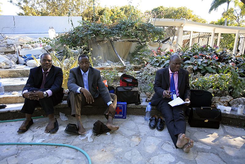 U.S. businessmen sit outside the Montana hotel after an earthquake in Port-au-Prince
