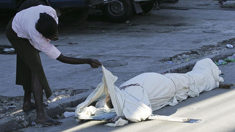 A woman checks a body after an earthquake in Port-au-Prince