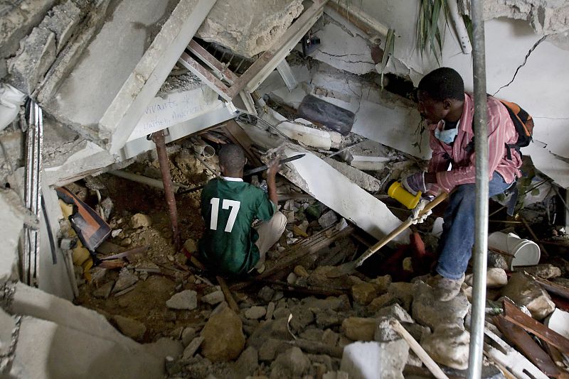 U.N. handout shows men trying to reach trapped survivors at the Montana hotel that collapsed after an earthquake in Port-au-Prince