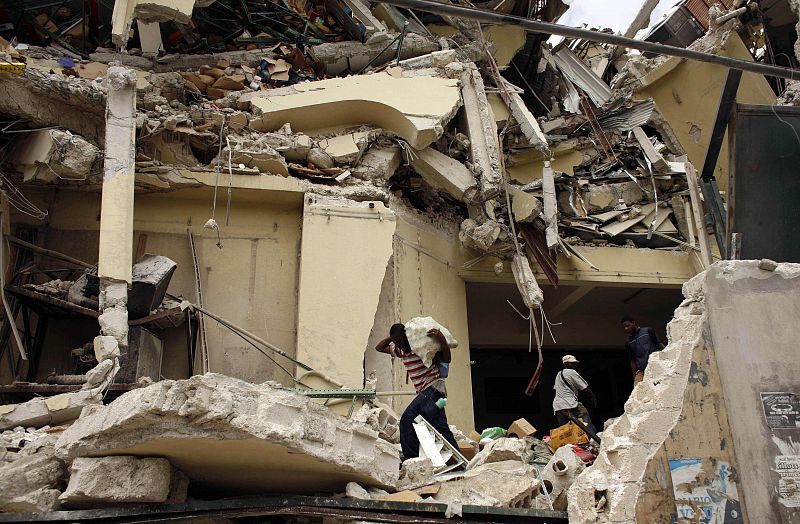 Residents take food from the destroyed Caribbean supermarket in downtown of Port-au-Prince after a major earthquake hit the capital