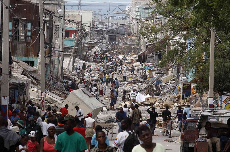 Residents walk at a destroyed area after a major earthquake hit the capital Port-au-Prince