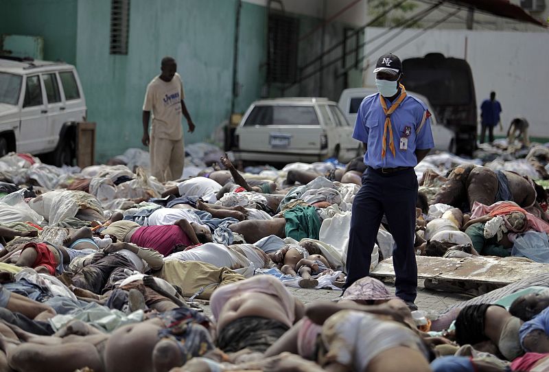 A resident stands next to dead bodies at the general hospital after a major earthquake hit the Haitian capital Port-au-Prince