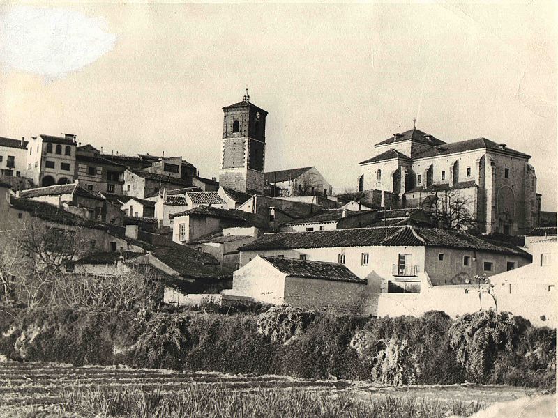 La torre del reloj, rodeada de varias casas.