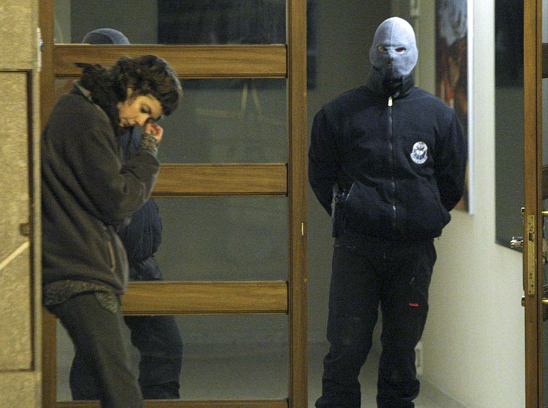 Un agente de la Ertzaintza vigila la entrada del portal de uno de los pisos registrados.