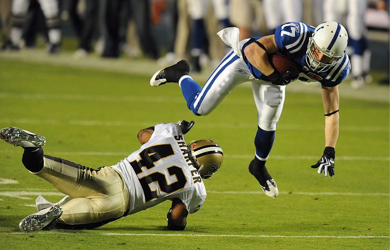 El jugador de los Potros de Indianápolis Austin Collie (d) es levantado por el defensa Darren Sharper (i) de los Santos de Nueva Orleans