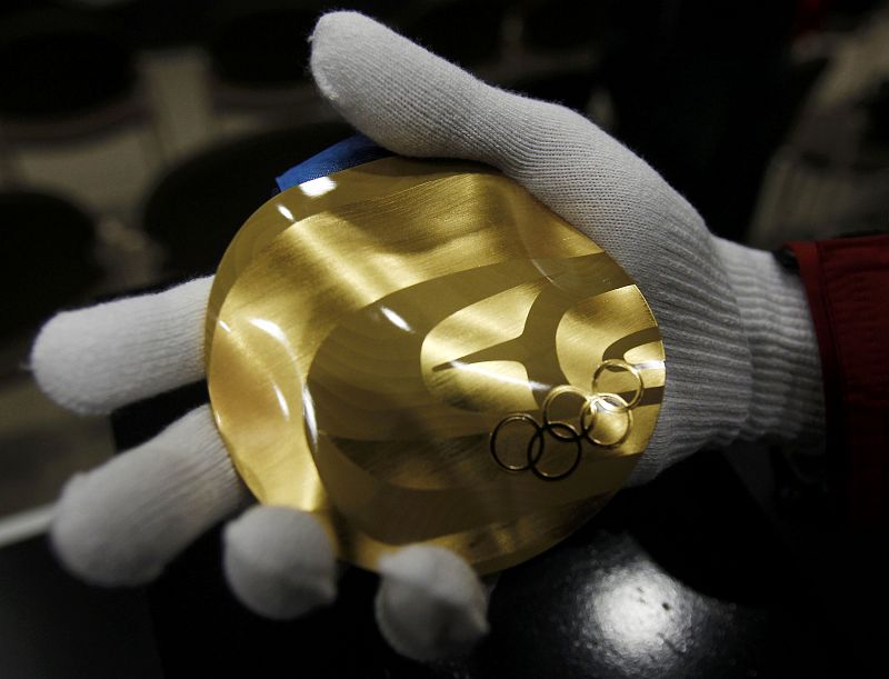 A visitor to the Royal Canadian Mint holds a replica of a Vancouver 2010 Winter Olympics gold medal on the second day of the Games