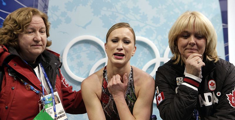 Canada's Rochette sits with her coach Perron and doctor Alleyne after finishing her routine in women's short programme figure skating event at Vancouver 2010 Winter Olympics