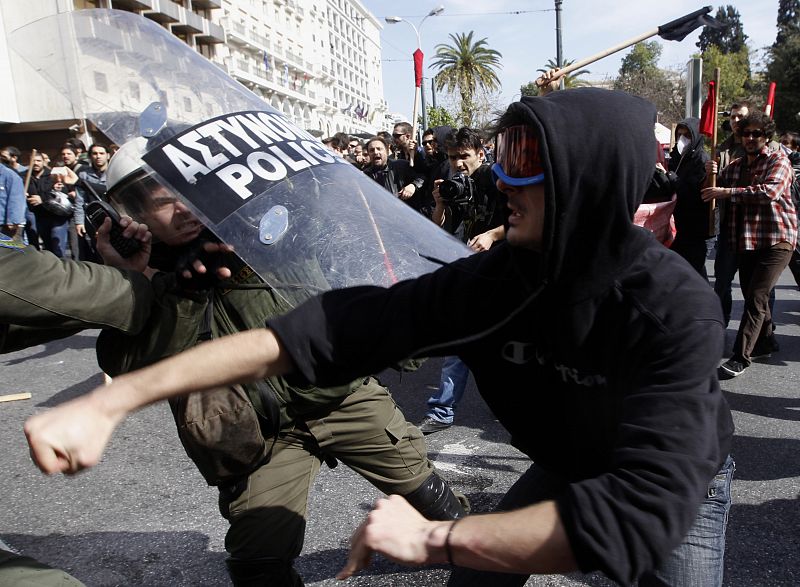 A protester clashes with riot policemen during an anti-government rally in Athens