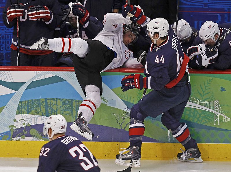 El jugador suizo Lemm acaba en el banquillo estadounidense durante el partido de Hockey que enfrentó a Suiza y EEUU.
