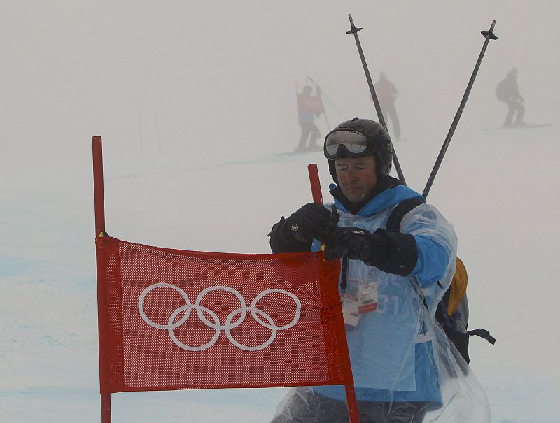 Un trabajador de la pista de Whistler retira una de las puertas del gigante femenino.