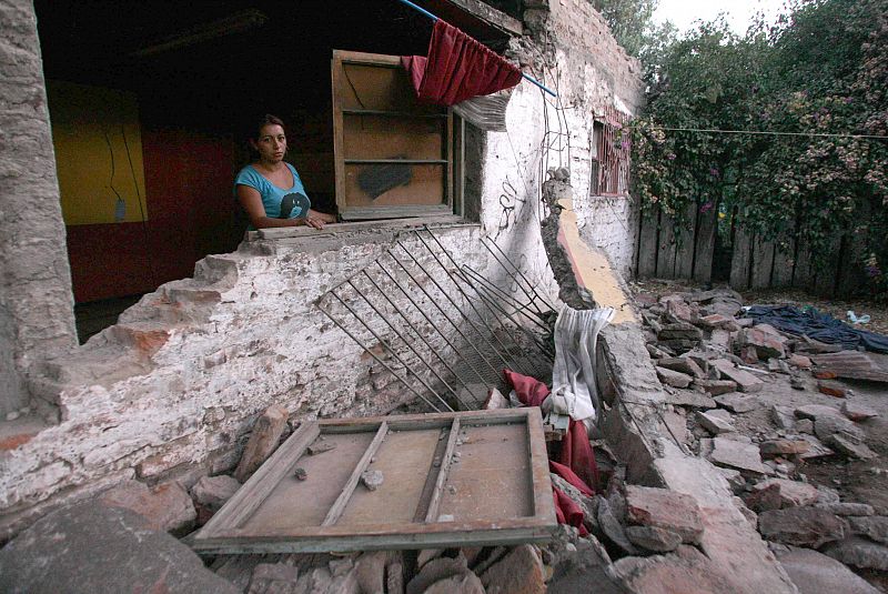 Una mujer permanece al interior de su vivienda destruida.