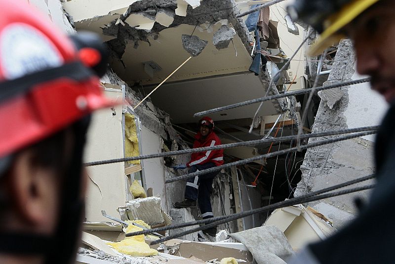 Bomberos chilenos trabajan en la búsqueda de sobrevivientes entre los escombros de un edificio.