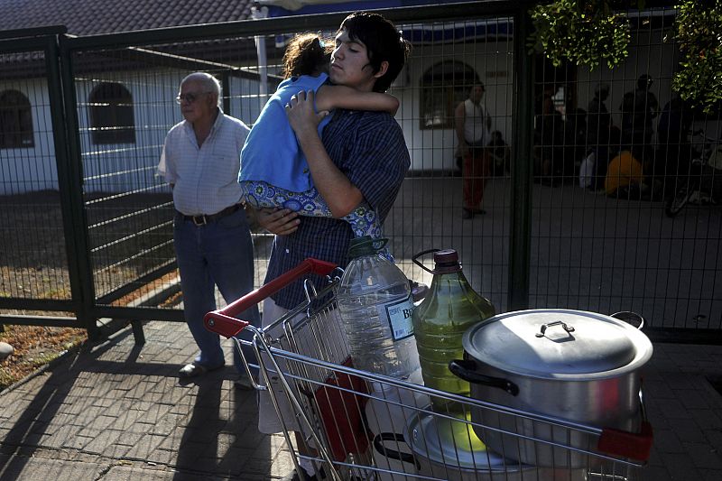 Una familia chilena regresa a casa con el agua que han recibido de un camión cisterna.