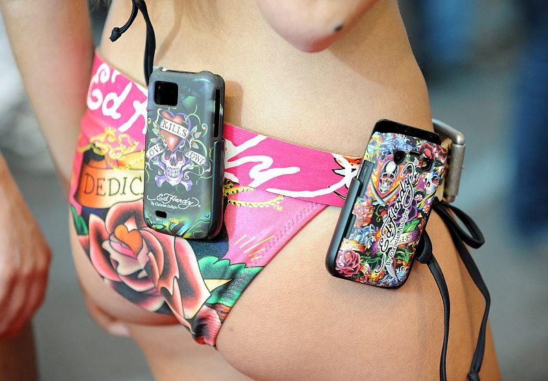 Una modelo en bikini exhibe fundas para el iPhone de Apple durante el CeBIT. Un total de 4.150 expositores de 68 países mostrarán sus productos en esta feria.