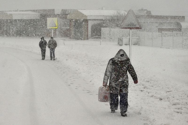 Varias personas caminan por la nieve cerca del puesto fronterizo de la Jonquera.